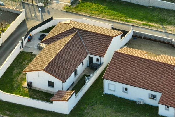 Vue aérienne d'une maison avec jardin clôturé.